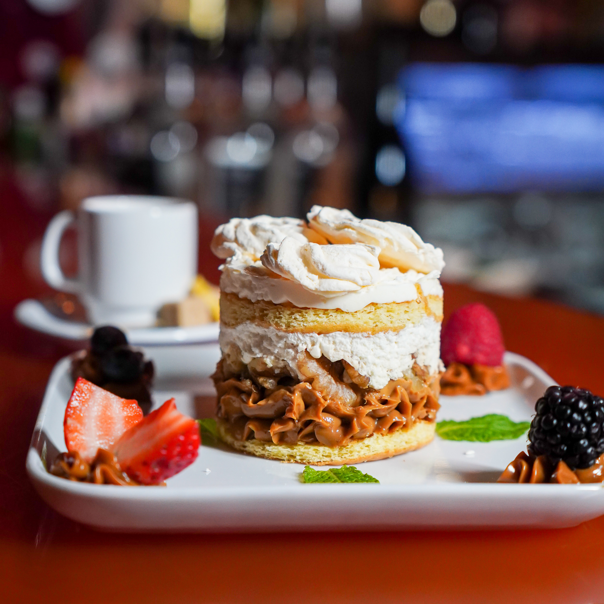 Renzo's signature chajá — layered sponge with dulce de leche, walnuts and chantilly, plated with fresh berries and mint